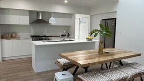 A modern kitchen with white cabinetry, a central island, a stainless steel stove, and a refrigerator.