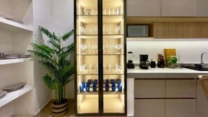 Una cocina moderna con una estantería para vinos integrada, una cafetera y una planta en maceta.