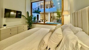 Un dormitorio con una cama grande, un televisor montado en la pared y vistas a una piscina y zona exterior.
