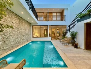 A modern house with a swimming pool, stone wall, and outdoor seating area. - Casa Quero by Wynwood House  (Cartagena)