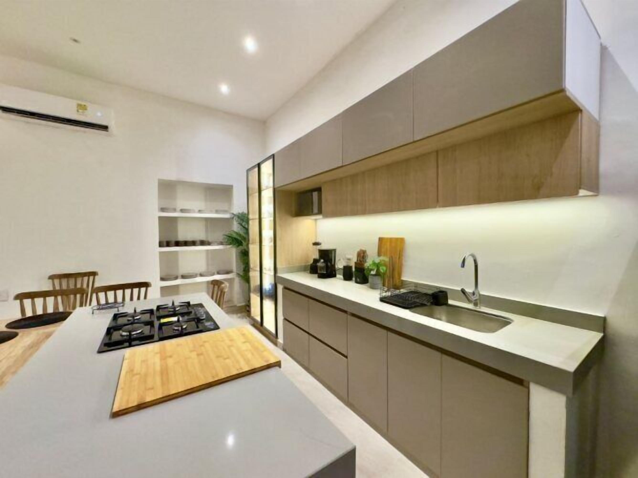 A modern kitchen with a central island, built-in cabinets, and a countertop with a sink and stove.