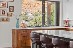 A kitchen with a large island, wooden cabinets, and a view of a rocky landscape.