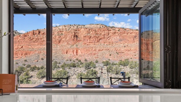 Un comedor con vistas a un paisaje de rocas rojas a través de amplios ventanales.
