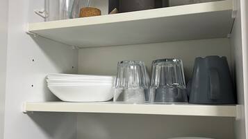 Un armario de cocina con repisas que contienen diversos utensilios de cocina.