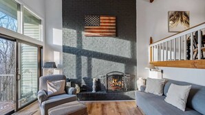 A living room with a fireplace, a sofa, a chair, and a large window.