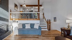 A loft-style bedroom with a built-in bed, a staircase, and a view of the living area.