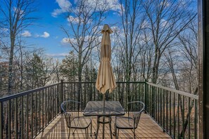 A wooden deck with a metal railing, a table with two chairs, and a beige umbrella. - Ski-In/Ski-Out Condo with Private Deck, Kingswood (Quechee)
