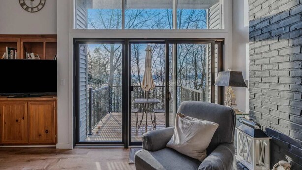 A spacious living room with a large sliding glass door leading to a deck, a television, and a cozy seating area.