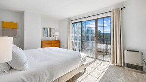 A bedroom with a bed, a dresser, a lamp, a window with curtains, and a radiator. - Condo with Fireplace, Sugar Hill (Quechee)