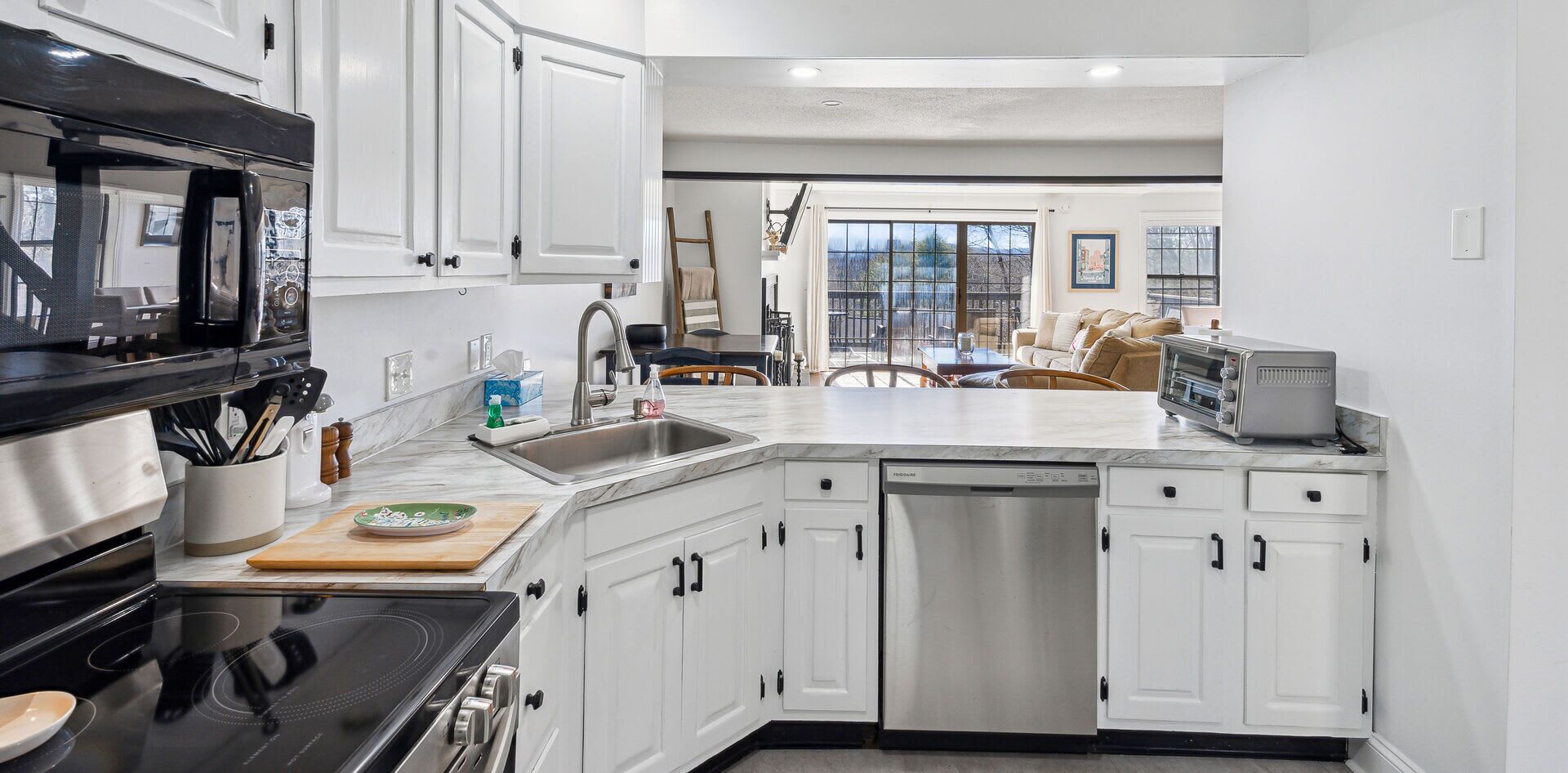 A modern kitchen with white cabinetry, a dishwasher, a microwave, and a toaster.