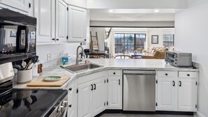 A modern kitchen with white cabinetry, a dishwasher, a microwave, and a toaster. - Condo with Fireplace, Sugar Hill (Quechee)