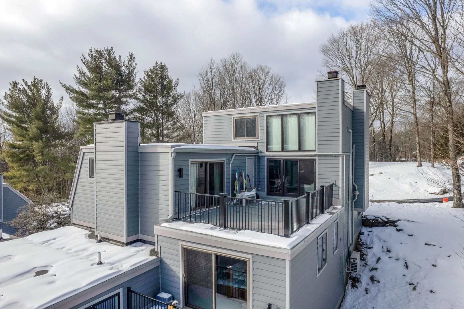 Ein modernes mehrgeschossiges Haus mit Balkon, großen Fenstern und einem Schornstein.