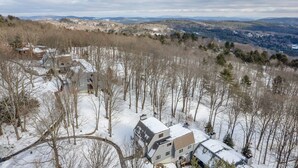 A residential area with houses surrounded by snow-covered trees and a hilly landscape in the background. - Townhouse, Mountain Views & Ski Access, Kingswood (Quechee)