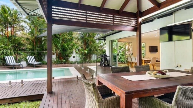 A covered outdoor area with a pool, dining table, and chairs.