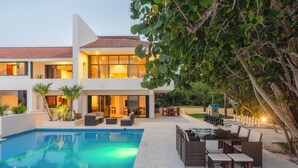 A modern two-story house with a swimming pool, outdoor seating, and a well-maintained garden.
