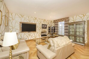 A modern living room with a sofa, a glass coffee table, a TV, and a decorative cabinet.
