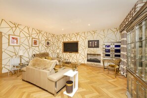 A modern living room with a sofa, a glass coffee table, a fireplace, and a decorative wall. - Argyl - Beautiful 3 Bedroom on York Place (Edinburgh)
