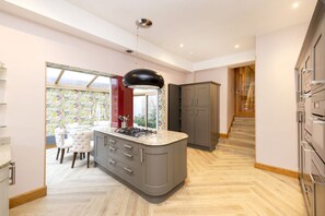 A modern kitchen with a central island, grey cabinets, and a dining area with white chairs.