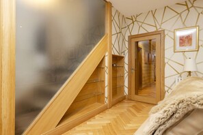A modern room with a wooden staircase, a glass cabinet, and a framed picture on the wall.