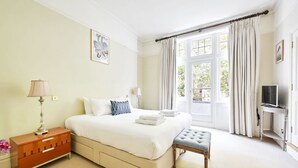 A bedroom with a bed, bedside table, lamp, and a window with curtains.
