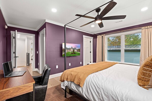 A bedroom with a bed, a desk with a laptop, a ceiling fan, and a window with curtains. - Luxe Retreat w/5star Beds & min from DT & Biltmore (Asheville)