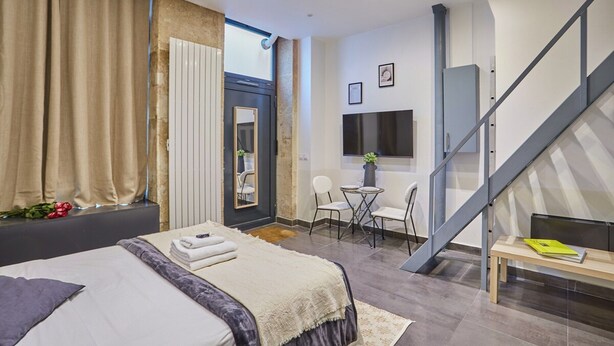 Quarto de hotel moderno com uma cama grande, uma escrivaninha e uma escada.