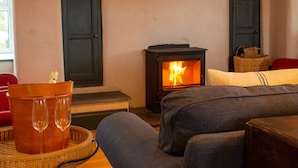 A cozy living room with a fireplace, a wicker table with glasses, and a red chair.