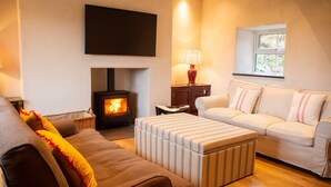 A cozy living room with a fireplace, a sofa, a loveseat, and a television mounted on the wall.