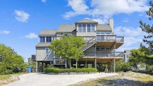 A two-story house with a balcony on the upper floor, a covered porch on the ground floor, and a clear sky.