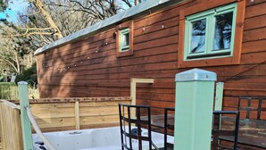A wooden cabin with a hot tub and a deck area.
