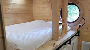 A compact bedroom with a bunk bed, a small window, and built-in storage cabinets.