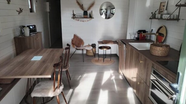 A compact kitchen with wooden cabinets, a central island, and a dining area with chairs.