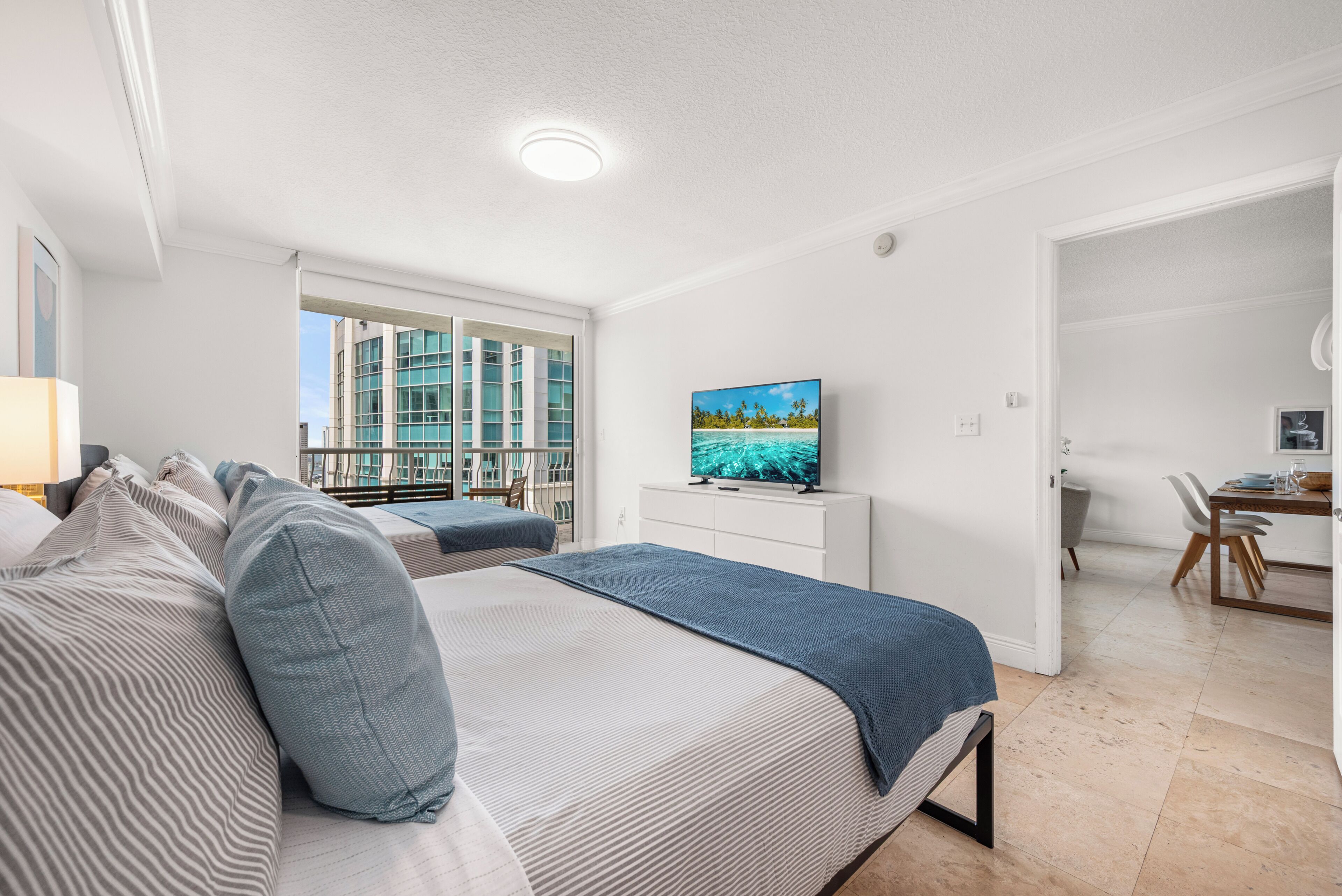 Una habitación de hotel moderna con cama, televisión, escritorio y vistas a la ciudad.