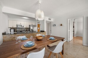 A modern kitchen with stainless steel appliances, a dining area with a wooden table and white chairs, and a bright pendant light. -  Centric 40thFloor Brickell Condo FREE parking by Palermo Home Miami (Miami)