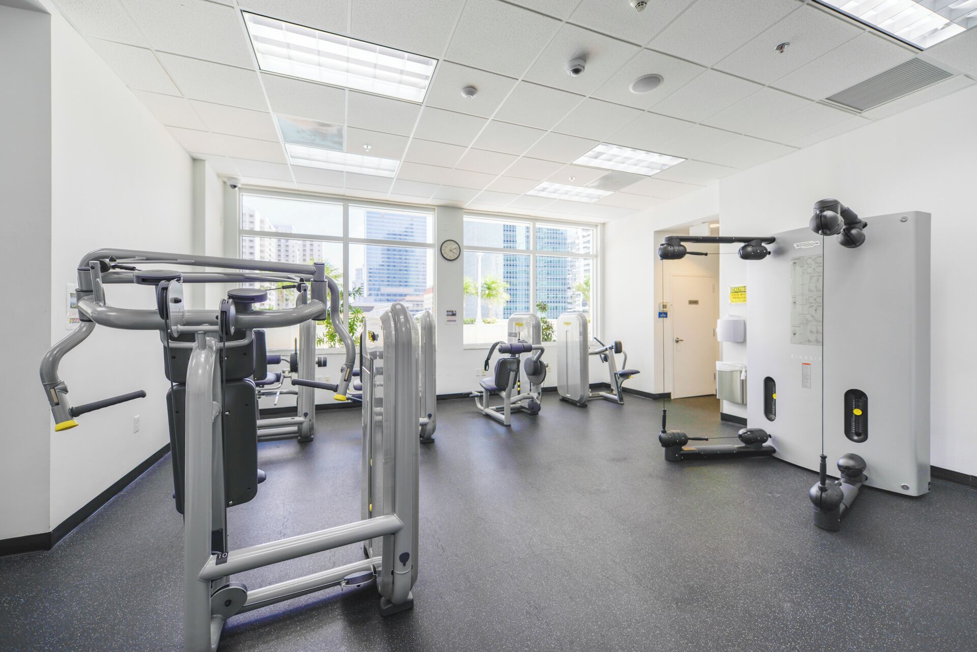 Een fitnessruimte met diverse trainingsapparaten, grote ramen en een schoon, modern design.