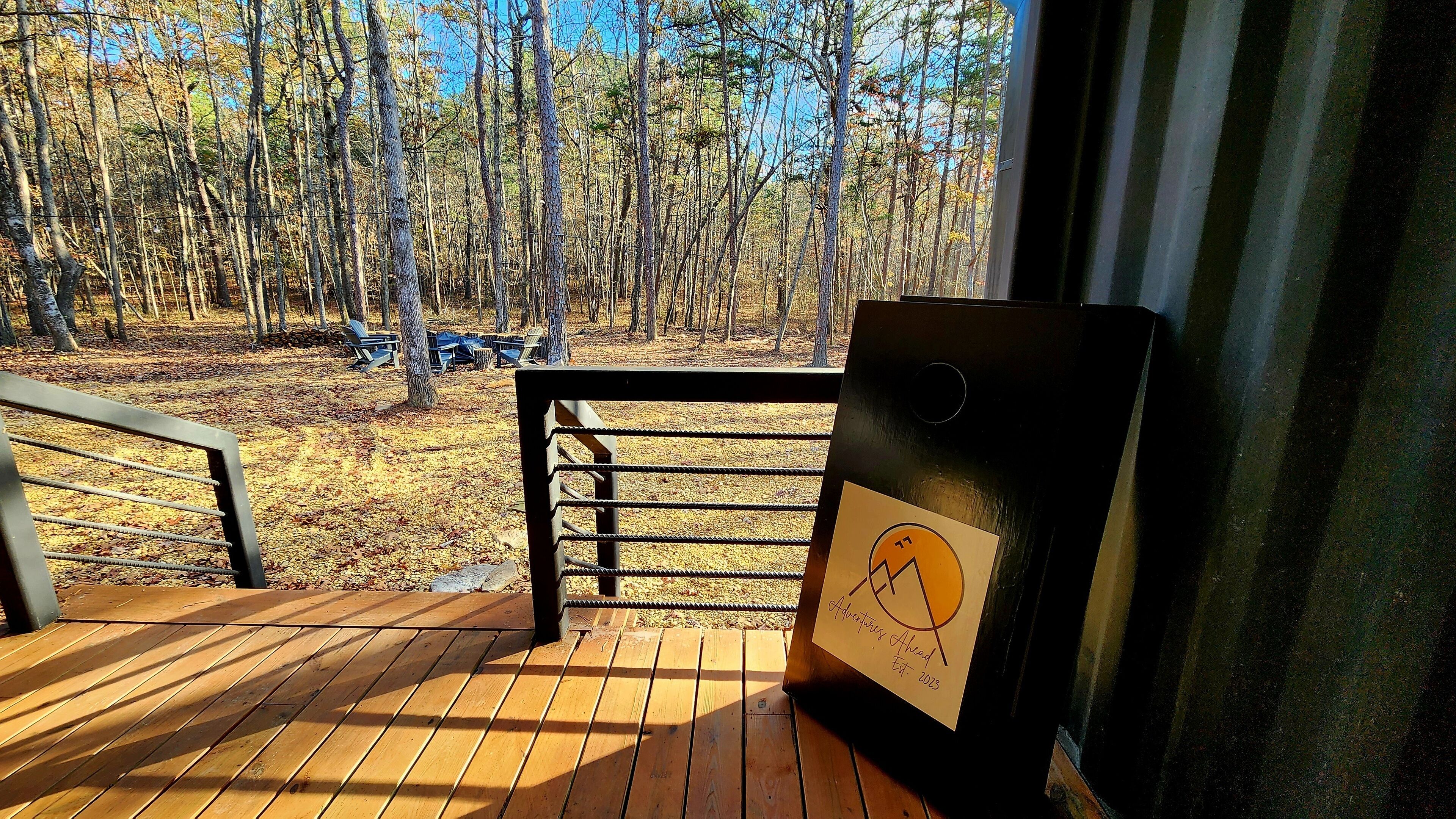 Eine Holzterrasse mit Metallgeländer, mit Blick auf ein bewaldetes Gebiet mit Bänken.