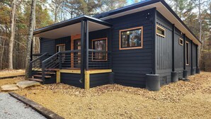 Une cabane dotée d’un porche couvert, d’un escalier et d’une allée gravillonnée.
