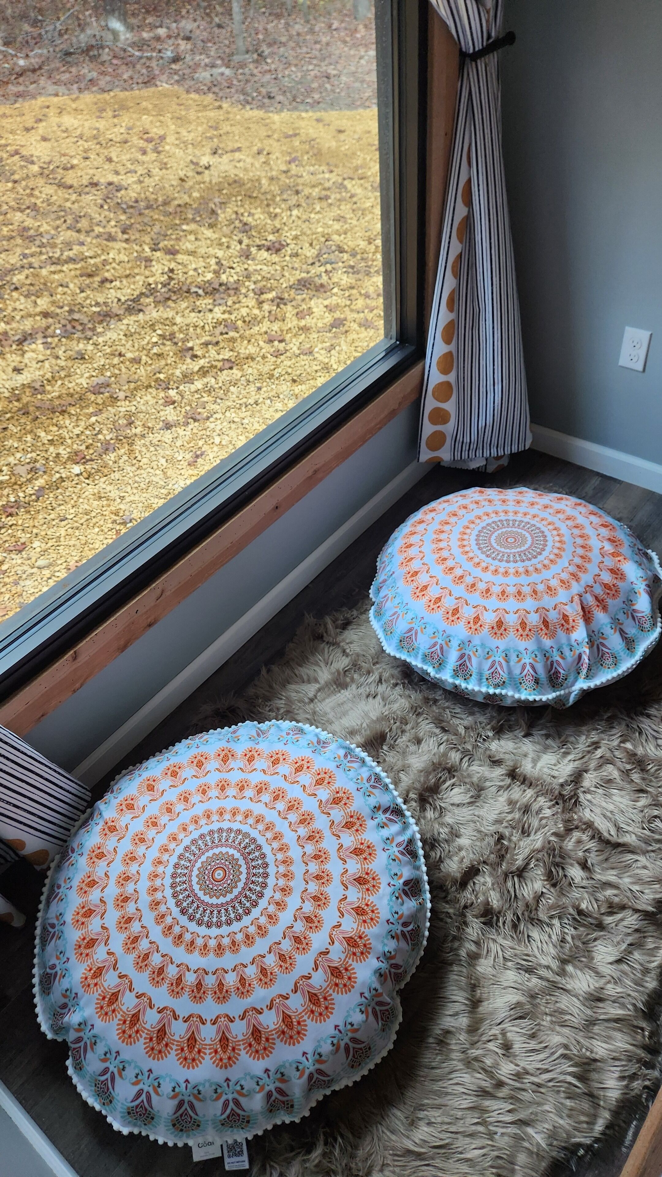 A window with a view of a gravel path and a fluffy rug inside.