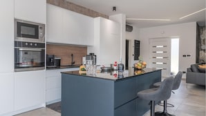 Une cuisine moderne avec des meubles blancs, un îlot central et un four encastré.