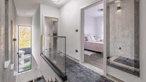 L’intérieur moderne d’un hôtel, avec une rambarde en verre, un escalier et une chambre à coucher comprenant un lit et des rideaux.