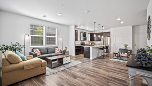 A modern living room with a sofa, coffee table, and a dining area with chairs and a table. - Close to USAFA & St Francis Hospital (Colorado Springs)