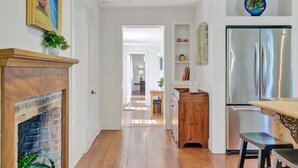 A kitchen with a stainless steel refrigerator, wooden cabinets, and a brick fireplace.