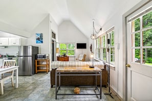 Una cocina con una mesa de comedor, un refrigerador, un microondas y un televisor.