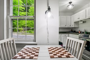 Una cocina con armarios blancos, una estufa y un ventanal con vistas al verdor.
