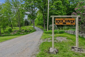 Un camino rural con un letrero de madera que dice 'Rock Haven' y que muestra dibujos de osos.