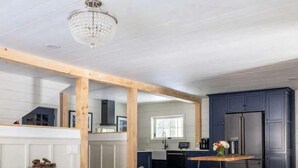 Un salon moderne comprenant un canapé, une table basse et un coin cuisine avec des meubles sombres et un réfrigérateur.