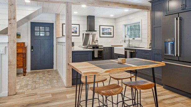 Une cuisine moderne avec une table et des tabourets en bois, un four encastré et un réfrigérateur.