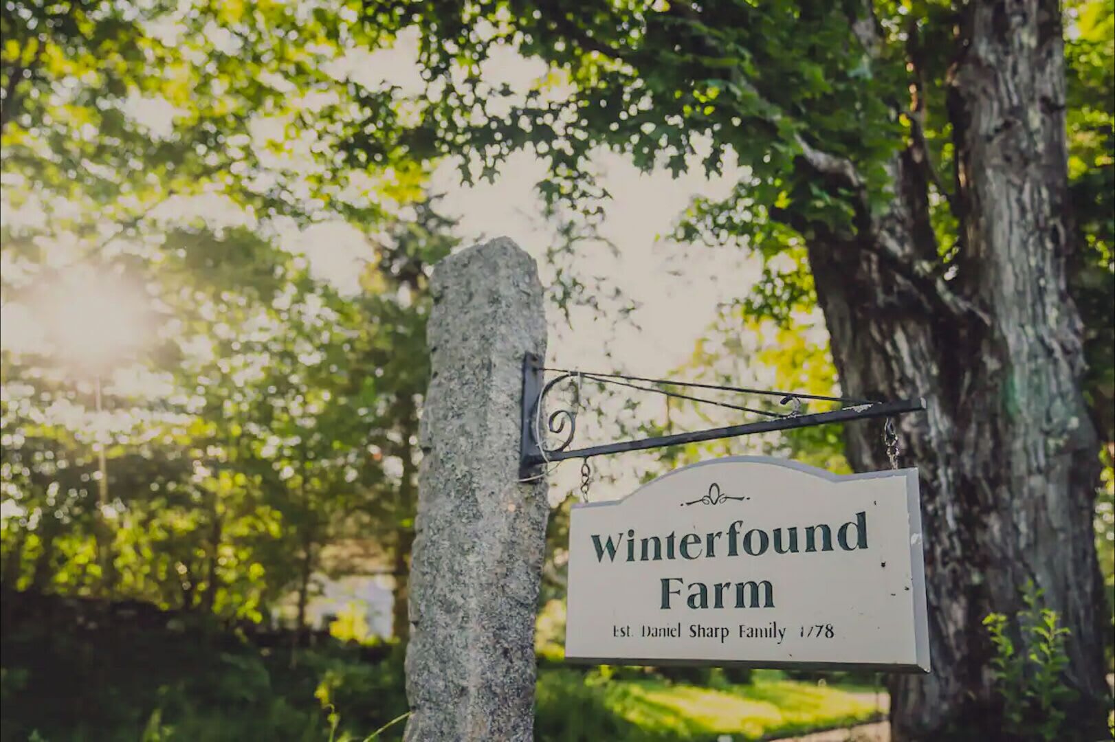 A sign for Winterfound Farm with a tree in the background.