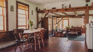 Ein rustikales Interieur mit einem Holzespeisetisch, Stühlen, einer Couch und einer Treppe.