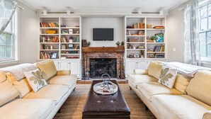 Ein Wohnzimmer mit zwei Sofas, einem Couchtisch, einem Kamin und Bücherregalen.